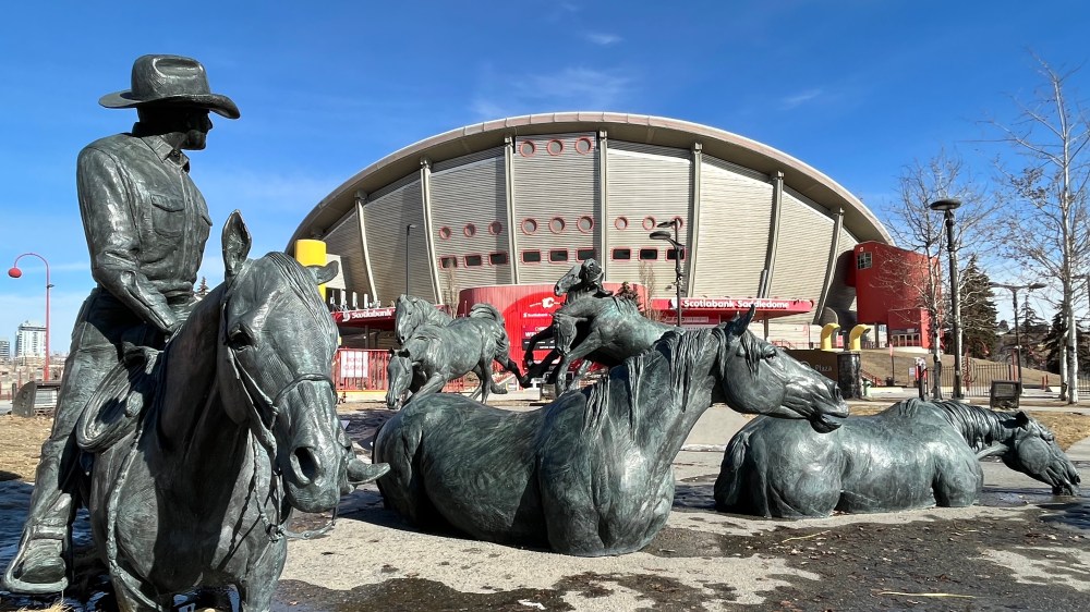 Cowboy looking back at the Saddledome in Stampede Park